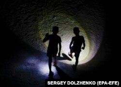 Дети играют в темноте с фонариками в жилом районе во время отключения электроэнергии в Киеве, Украина, 26 августа 2024 года