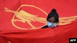 Девушка на фоне флага &quot;Национальной лиги за демократию&quot; во время протеста против военного переворота в Янгоне 7 февраля
