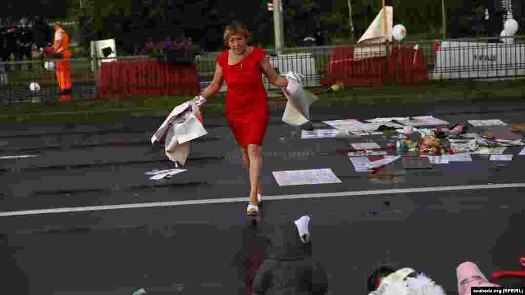 Женщина помогает убирать остатки транспарантов и предметов перформанса, "чтобы потом не сказали, что мы вандалы"